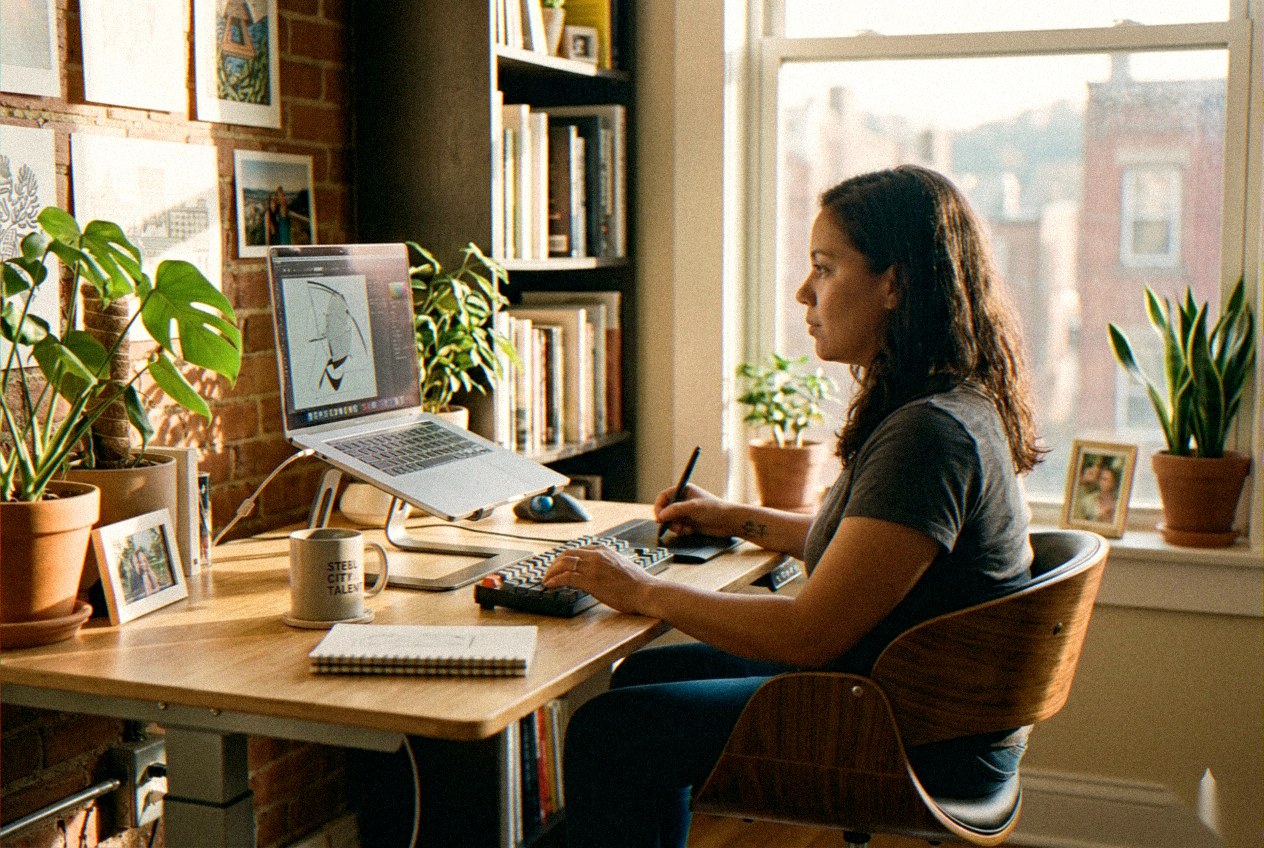 Creative designer working in a home studio with a secondary monitor and camera.